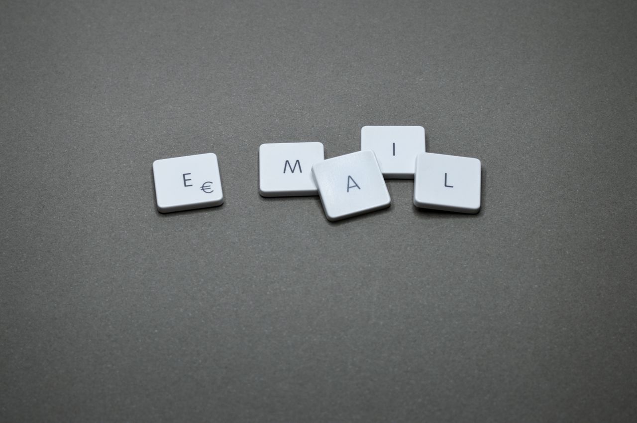 Services-03 Close-up of the word email formed with letter tiles on a gray surface.